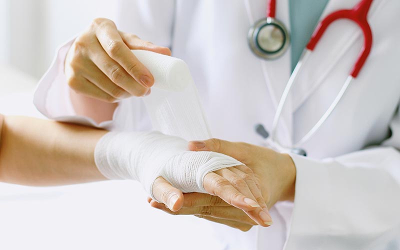 Orthopedic injury doctor wrapping a wrist - Common Orthopedic Injuries To Avoid This Summer